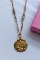 Zbliżenie na naszyjnik zodiakalny Wagi: medalion z wypukłym symbolem wagi i kolorowymi detalami, złocisty łańcuszek oraz akwamaryn i kamień księżycowy.
