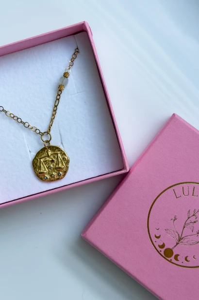 Naszyjnik dla Wagi z kamieniem księżycowym i medalionem z symbolem znaku zodiaku, ułożony w różowym pudełku Lulobelia.