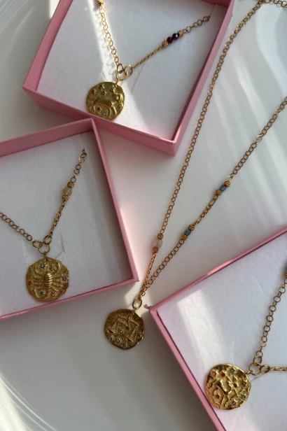 Naszyjnik Skorpiona z medalionem przedstawiającym skorpiona, pokazany w różowym pudełku obok innych modeli z kolekcji zodiakalnej Lulobelia.